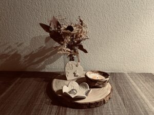 1 bougie allumée en terre mêlée, une coupelle fleur dentelles et un coeur déco à suspendre