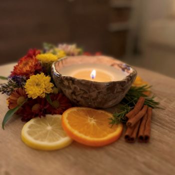 Une photo d'ambiance montrant ma bougie stracciatella entourée de fleurs, bâtons de cannelle, agrumes).