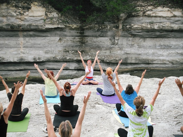 groupe de Yoga assis sur un sol de roche bras en l'air à côté d'une rivière