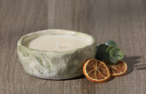 Bougie en céramique bicolore vert et blanc avec des rondelles d'orange séchées et un brin d'eucalyptus en décor
