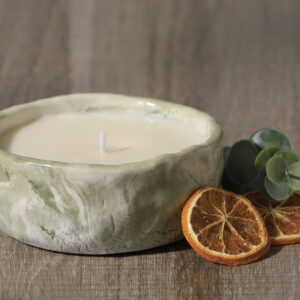 Bougie en céramique bicolore vert et blanc avec des rondelles d'orange séchées et un brin d'eucalyptus en décor