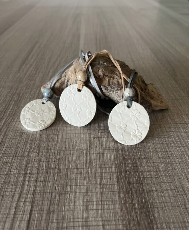 3 pendentifs en céramique a motifs fleurs ornes d'une perle en céramique et d'un cordon en suedine